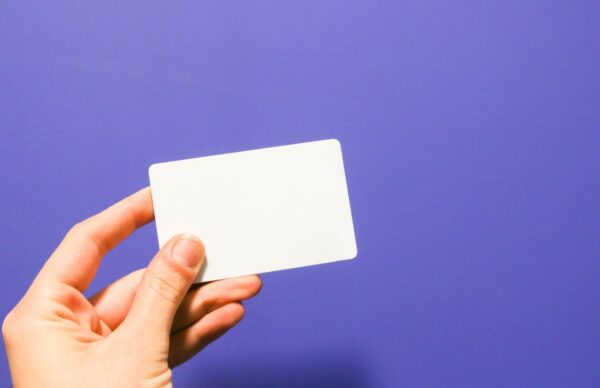 a hand holding a white business card against a purple background